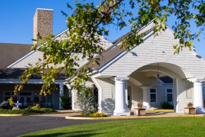 Our Mission & Philosophy 1 Front entrance building w/big white pillars & a covered drive at Peconic Landing